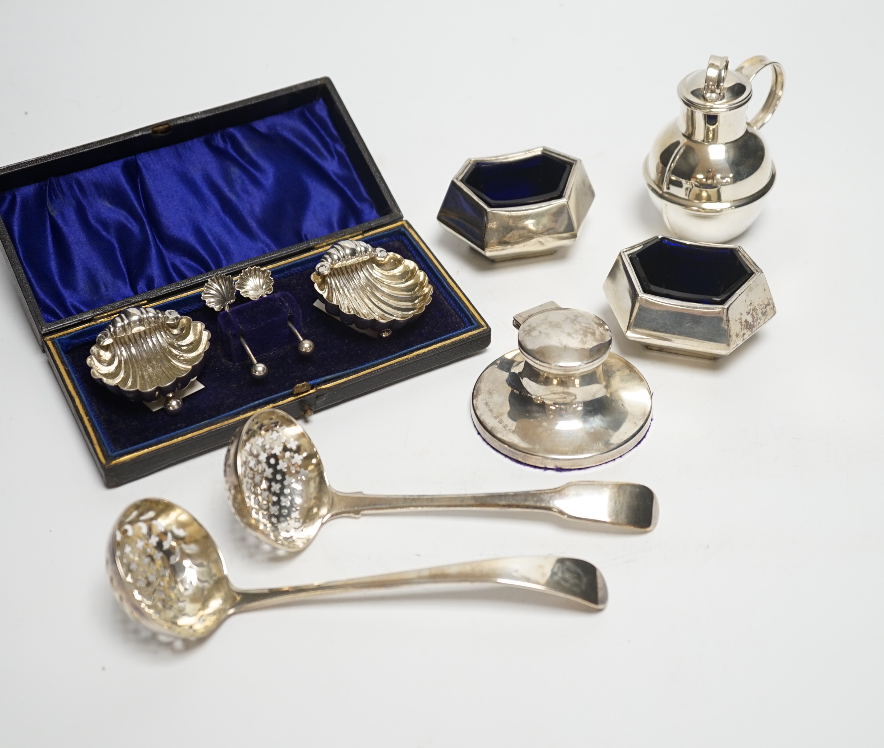 A cased pair of silver salts, one other pair of salts, a Guernsey miniature silver milk jug, an inkwell and two silver sifter ladles.